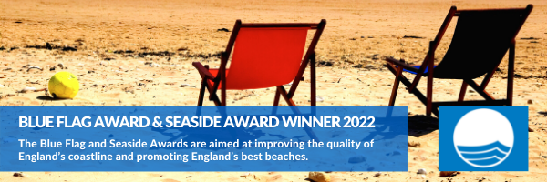 Blue Flag Awards & Seaside Award Winner 2022. The Blue Flag and Seaside Awards are aimed at improving the quality of England's coastline and promoting England's best beaches. Image shows two deckchairs on a sandy beach. 