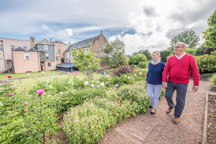 An older couple walking hand in hand through the gardens of Torre Abbey.
