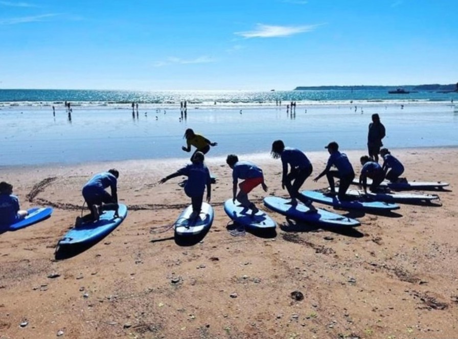 Children on a beach practising surfing