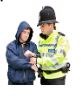 A policeman arresting a man with a hoody on up over his head