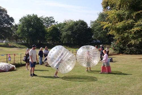 Two children playing while wearing inflatable body bumper balls.